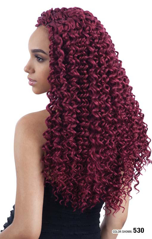 Woman modeling Freetress Beach Curl 18" crochet braid hair, featuring long, voluminous dark red curls cascading down her b...
