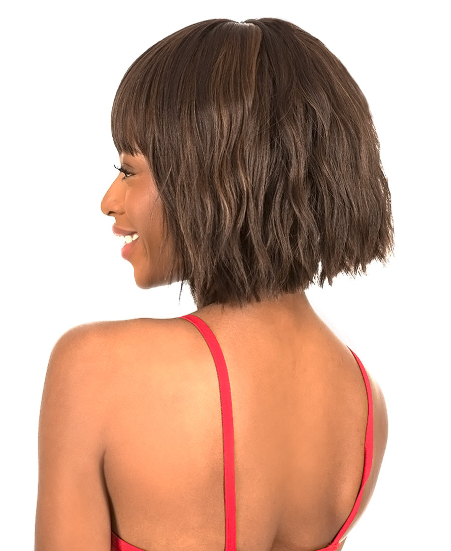 Smiling woman wearing New Born Free CUTIE TOO 204 β Quick Style Wig. It's a chin-length, dark brown wavy bob with bangs.