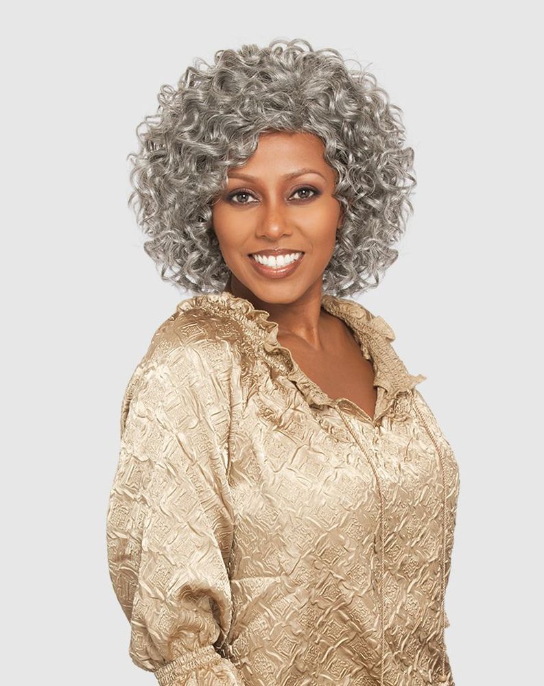 Smiling woman wearing Vanessa FREEDA Synthetic Wig, featuring a short, voluminous gray curly hairstyle, chin-length.
