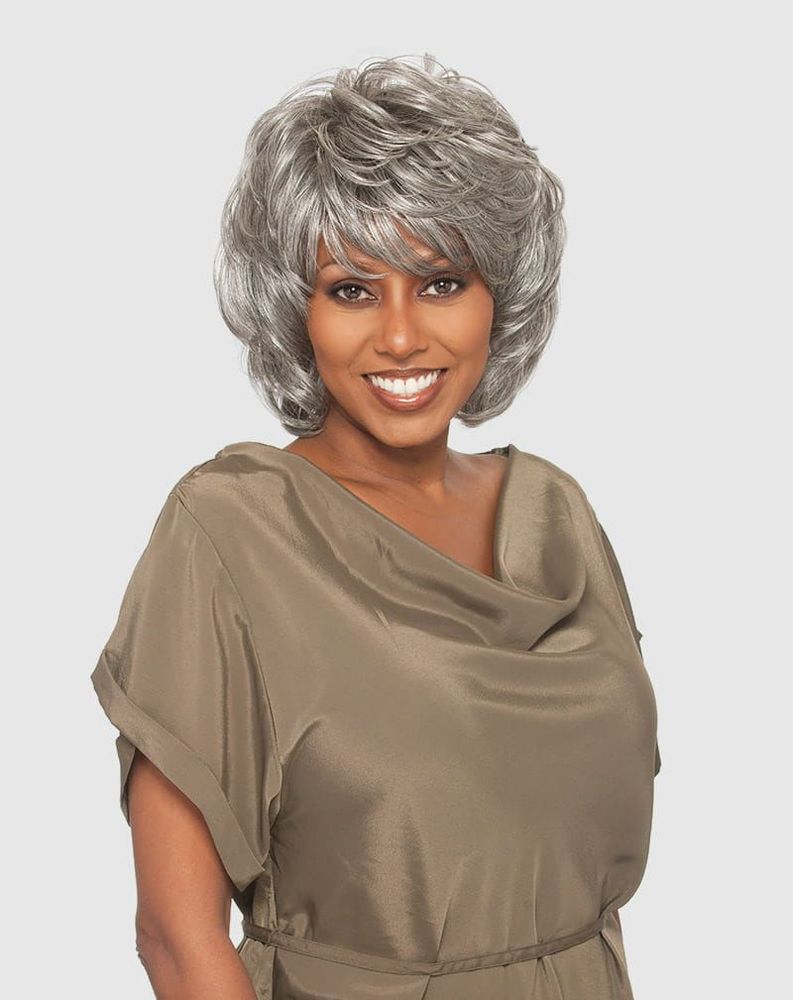 Smiling woman wears the Vanessa JINNY Synthetic Wig, a short, voluminous silver-gray layered bob with bangs.