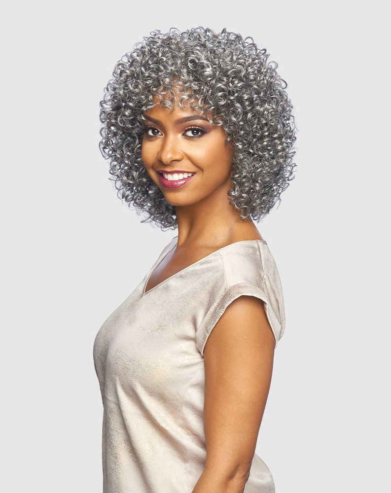 Woman models Vanessa MIKO Chic Cut wig. Short, voluminous silver-grey curls frame her face, with a curly fringe.