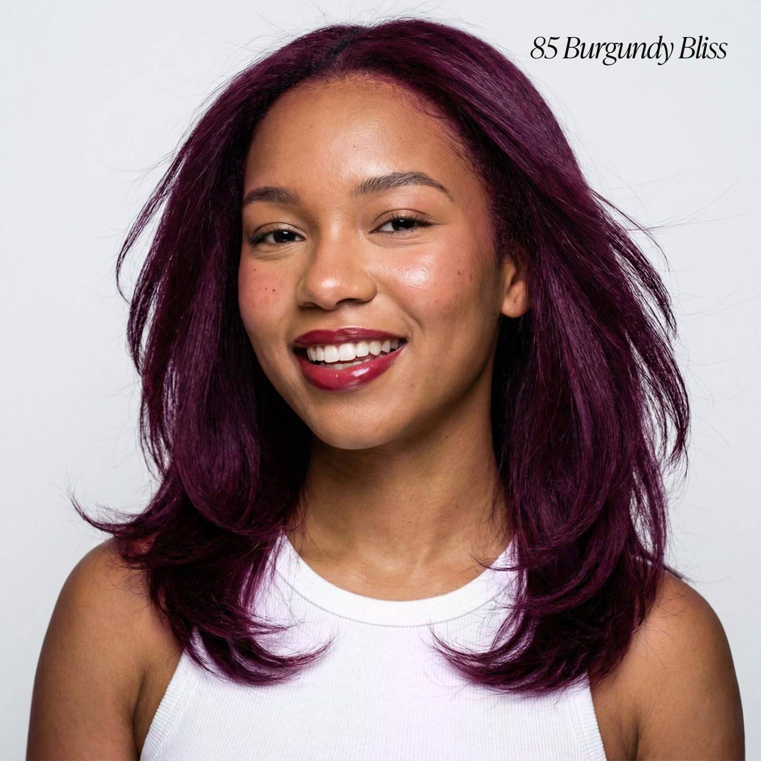 Smiling woman with shoulder-length, layered hair dyed rich Adore #85 Burgundy Bliss, styled with soft waves.