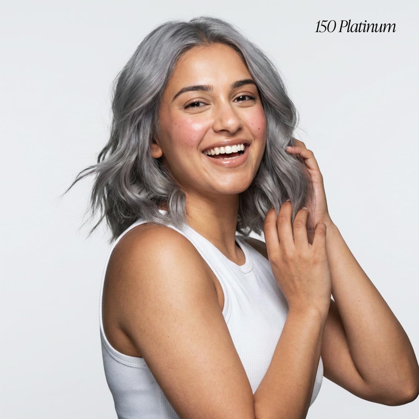 A happy woman shows off wavy, shoulder-length Creative Image Adore #150 Platinum silver hair, touching it playfully.