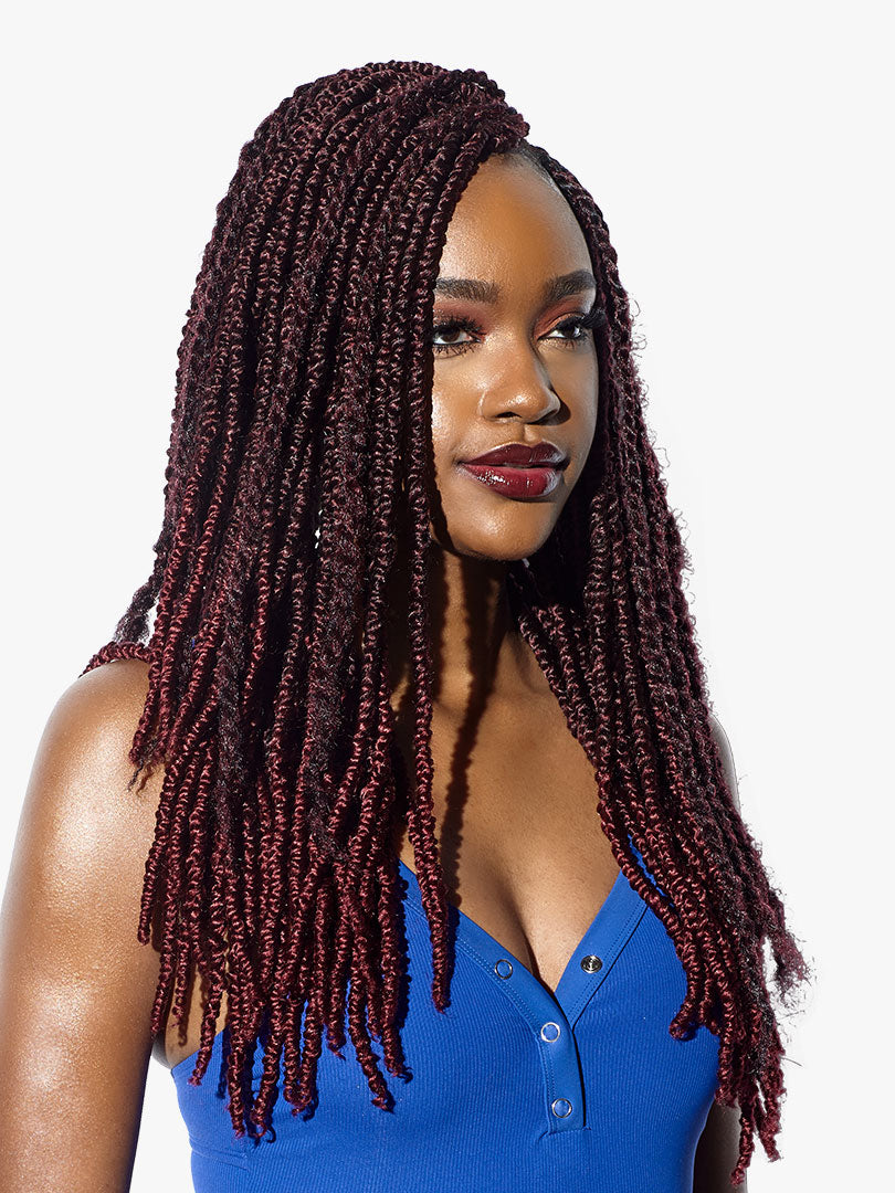 A woman wears long, dark red Ruwa 2X Jamaican Twist braids, styled over her shoulders and chest.