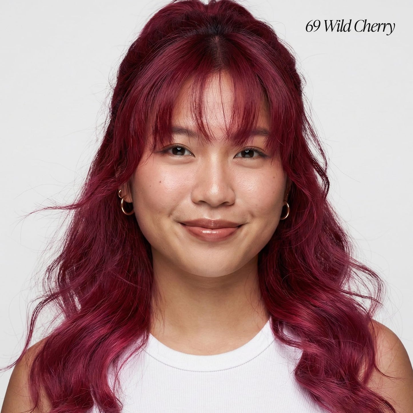 Smiling woman with long, wavy Creative Image Adore Wild Cherry hair, styled half-up with bangs.