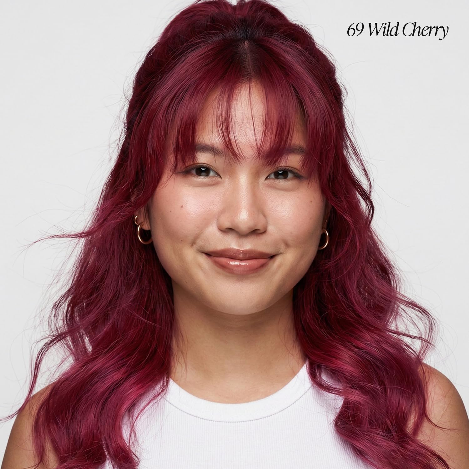 Smiling woman with long, wavy Creative Image Adore Wild Cherry hair, styled half-up with bangs.