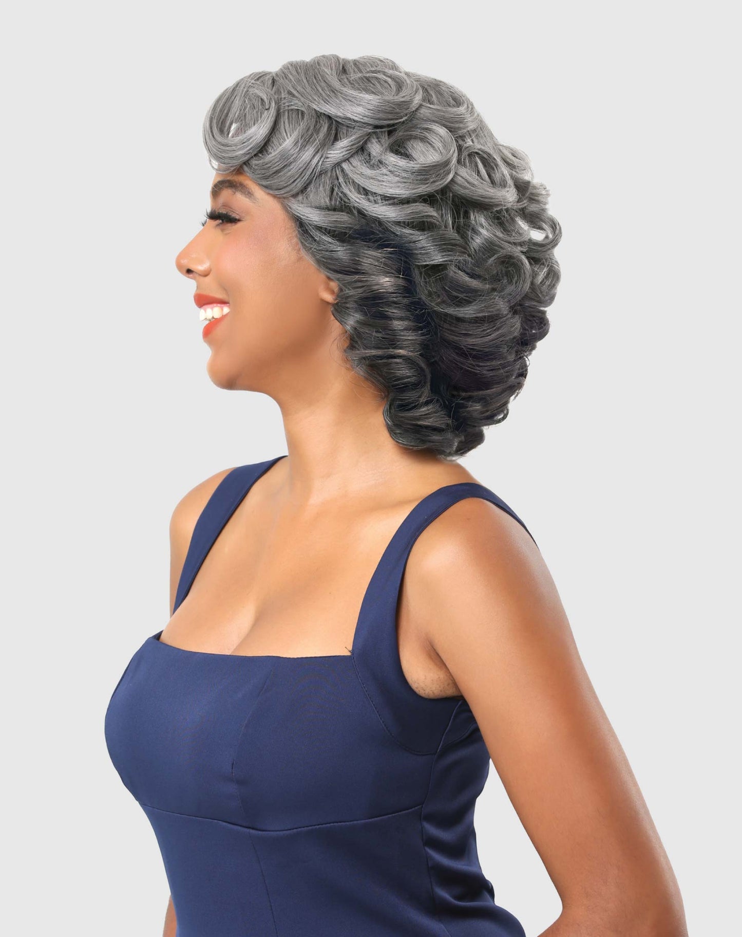 Smiling woman wears Zayla Deep J Part Synthetic Lace Front Wig: short, grey, voluminous hair with tightly defined curls.