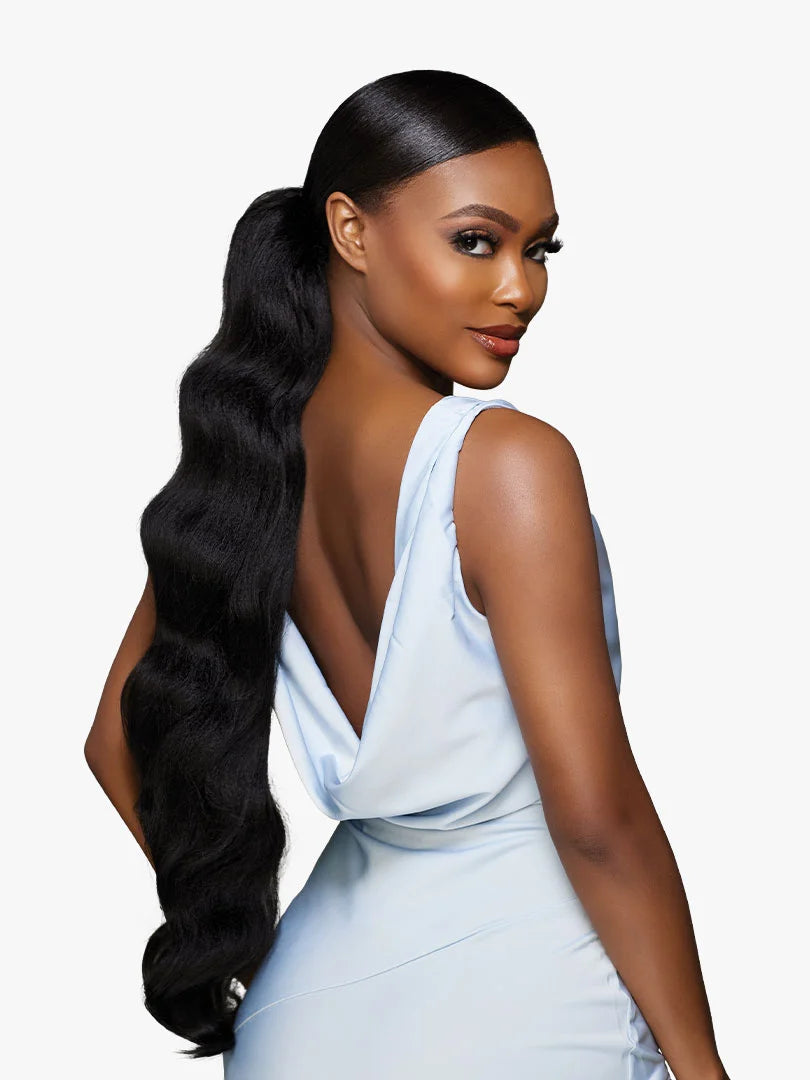 A woman models GLAMORA Glam Updo Unit 6, a sleek high black ponytail with long, voluminous body waves.