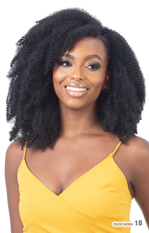 Smiling woman wearing Freetress 3X Pre-Fluffed Poppin' Twist 16" hair. It's voluminous, black, and shoulder-length with de...