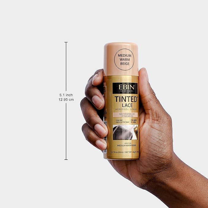 Hand holds EBIN Tinted Lace Spray packaging. Gold aerosol bottle with beige cap labeled Medium Warm Beige.