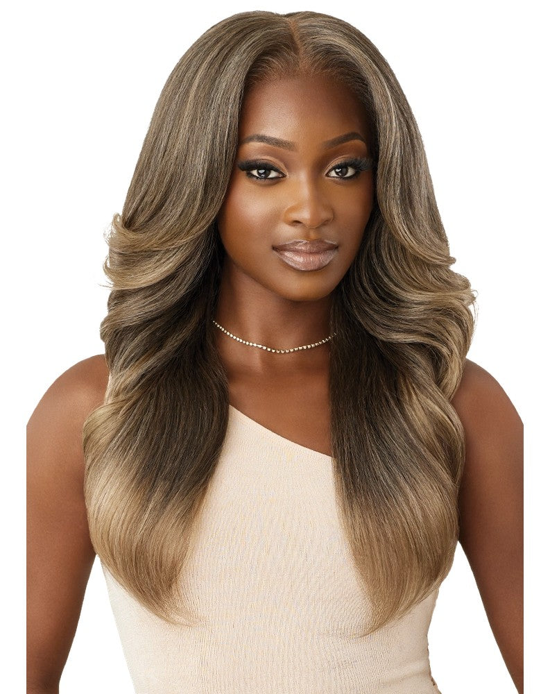 A woman models the Perfect Hairline TAYON wig, featuring long, ash brown to blonde ombre hair, styled with voluminous, sof...