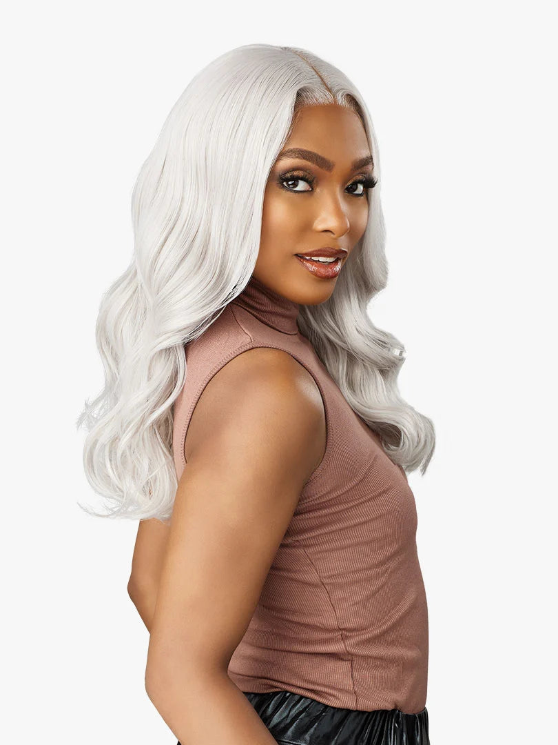 A woman wears the Shear Muse Gold Krush Lanisha wig: long, wavy silver-gray hair with a center part.
