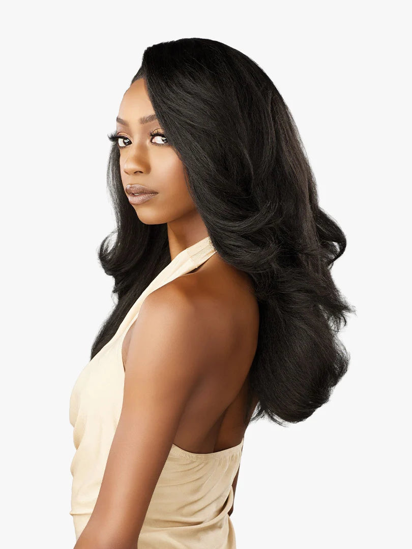 Woman models Cloud 9 What Lace? Evadra synthetic wig. Voluminous, long black hair with a deep side part and soft, layered ...