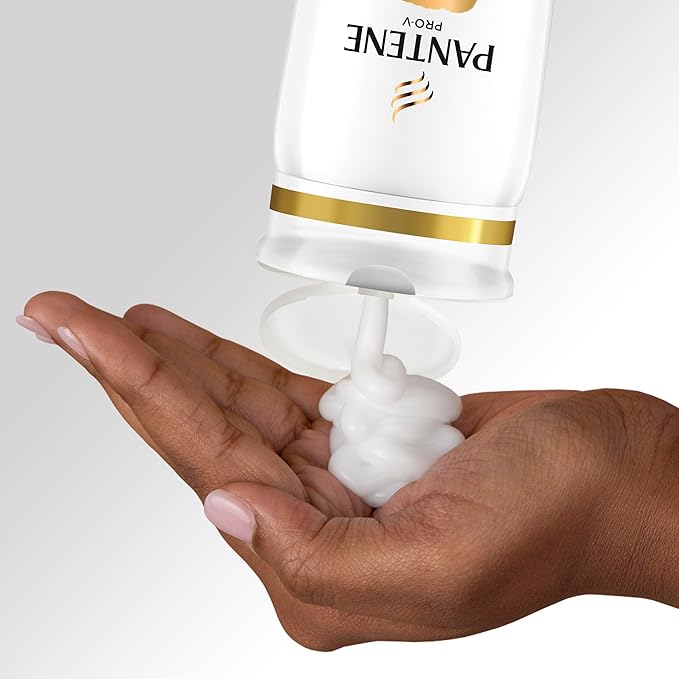 A cupped hand receives white, foamy Pantene Pro-V Daily Moisture Shampoo from its inverted bottle.