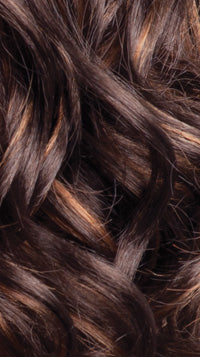 Close-up of Freetress Presto Curl 26" hair, showing wavy dark brown strands with caramel highlights.