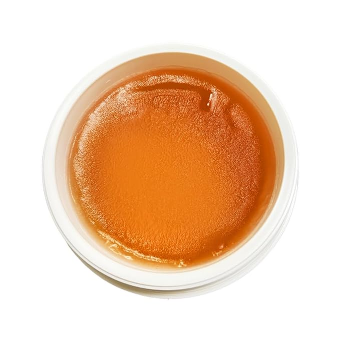 Top view of PINK LEMON BRAIDING GEL: a translucent, amber-orange gel with a smooth surface in a white tub.
